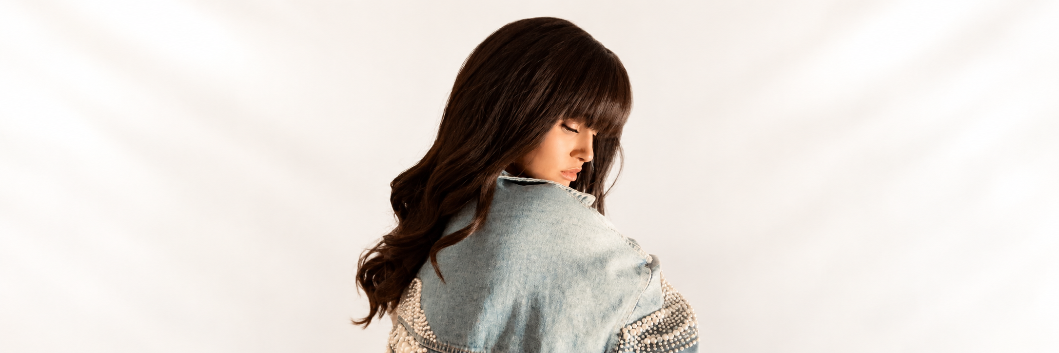 Editorial portrait of Victoria Beauty atelier muse turned away in soft champagne light.