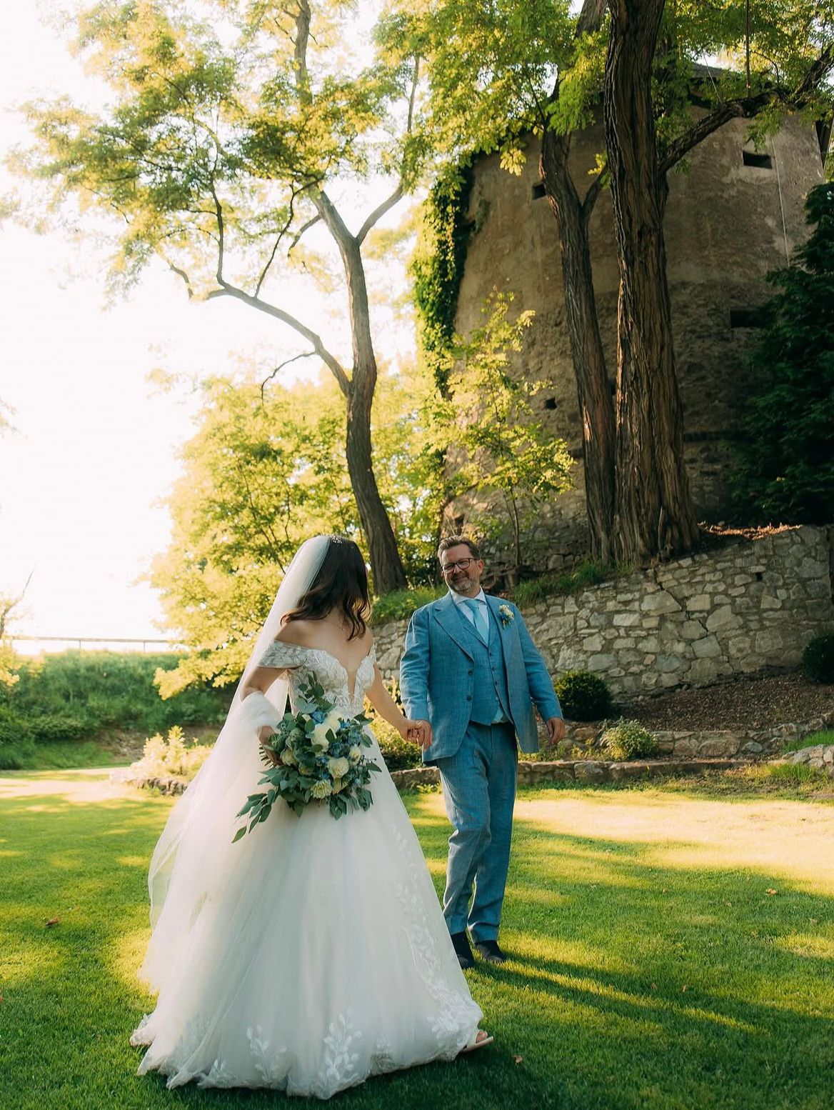 Destination wedding — bride and groom in a sunlit garden setting.