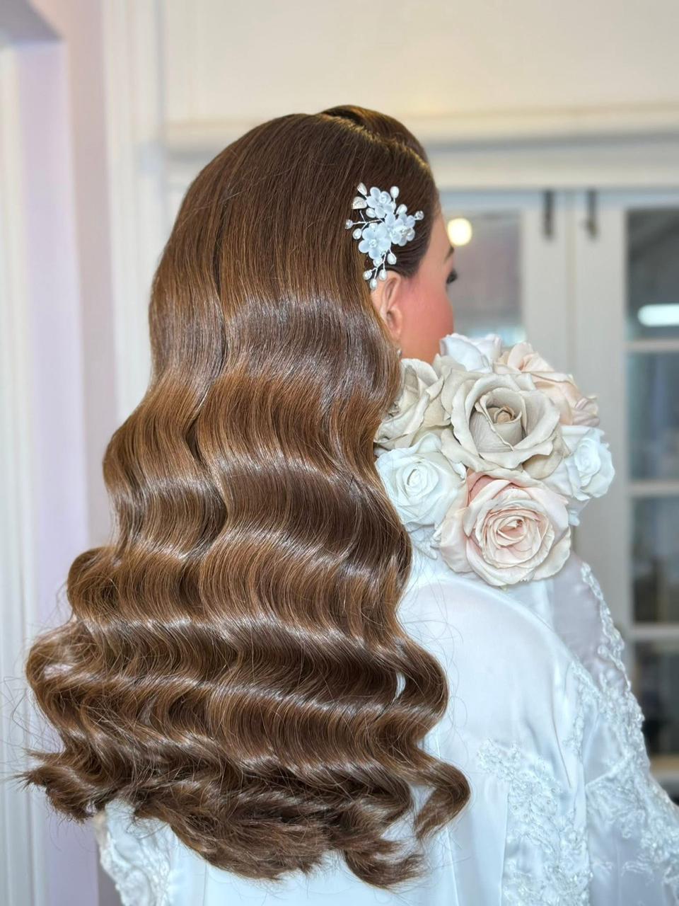 Bridal hair with floral hairpiece and polished waves.