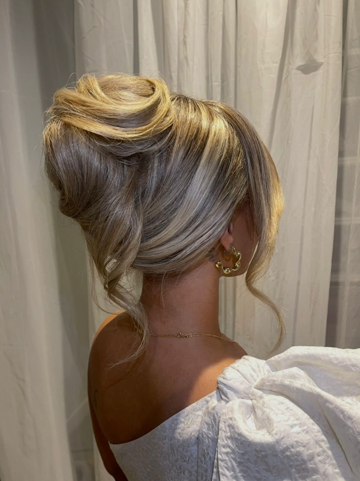 Event hair styling — voluminous French twist updo with gold hoop earring.