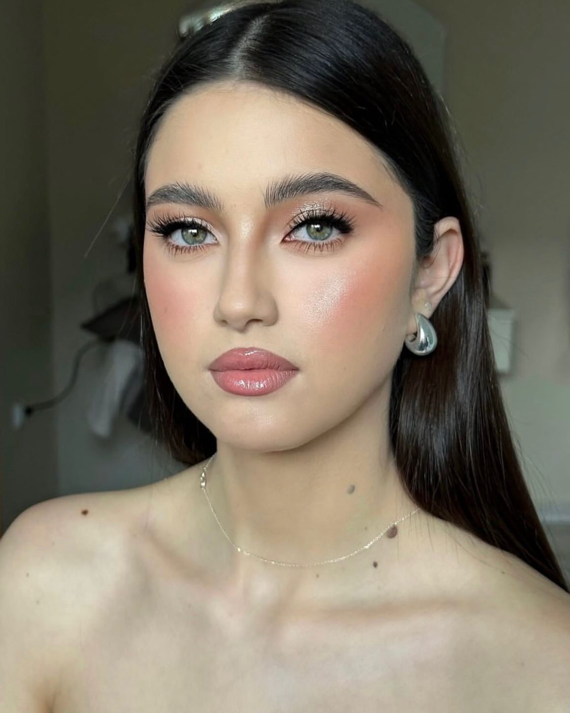 Soft glam close-up — luminous skin, glossy nude lip, soft pink blush.